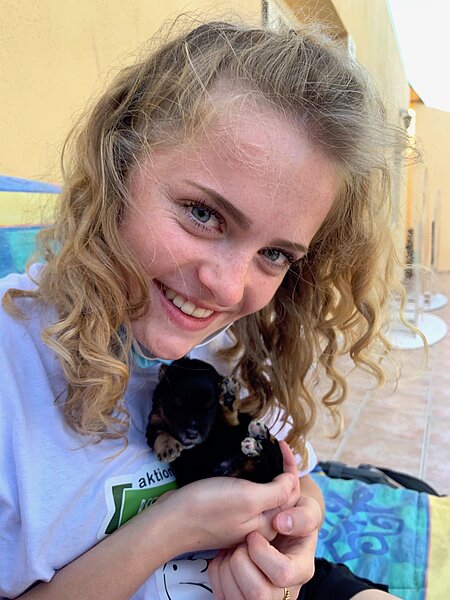 Schülerin mit einem Hundewelpen auf dem Arm